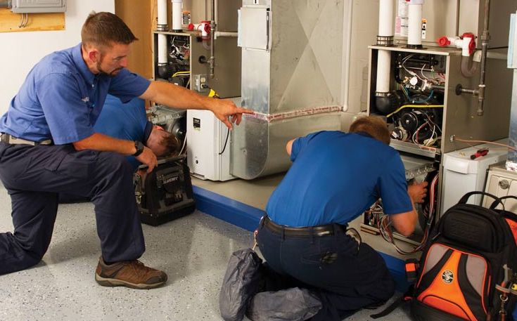 Two technicians repair furnace.