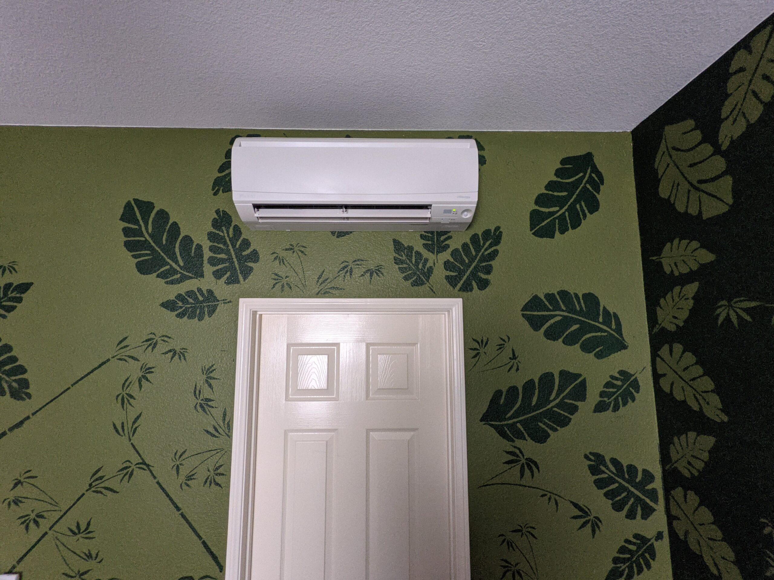 Mini-split air conditioner indoor unit installed by Accord Air in San Diego, with green wallpaper featuring green leaves.