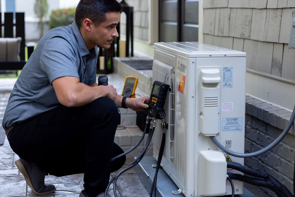 Mitsubishi mini-split installer checks the outdoor unit.