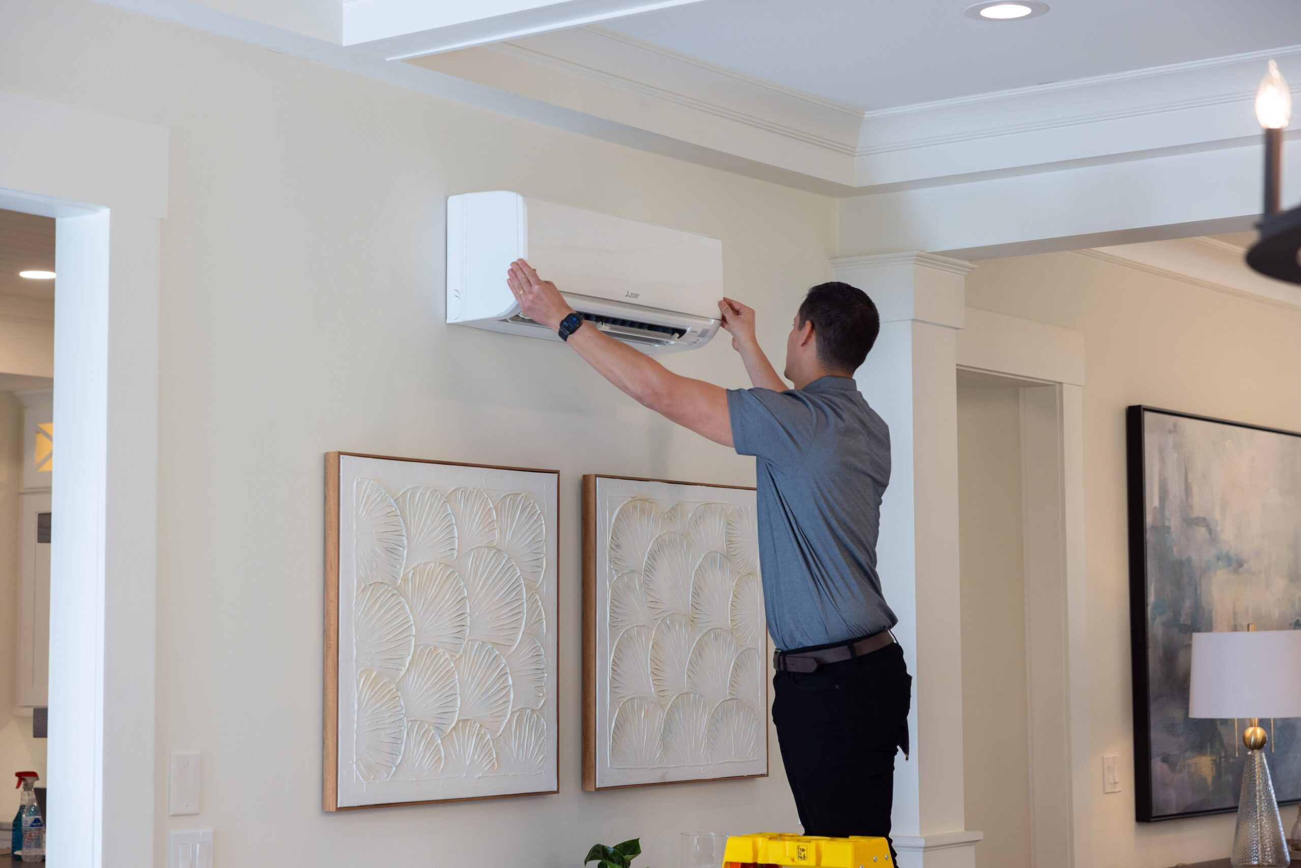 An HVAC installer installs a wall-mounted Mitsubishi mini-split.