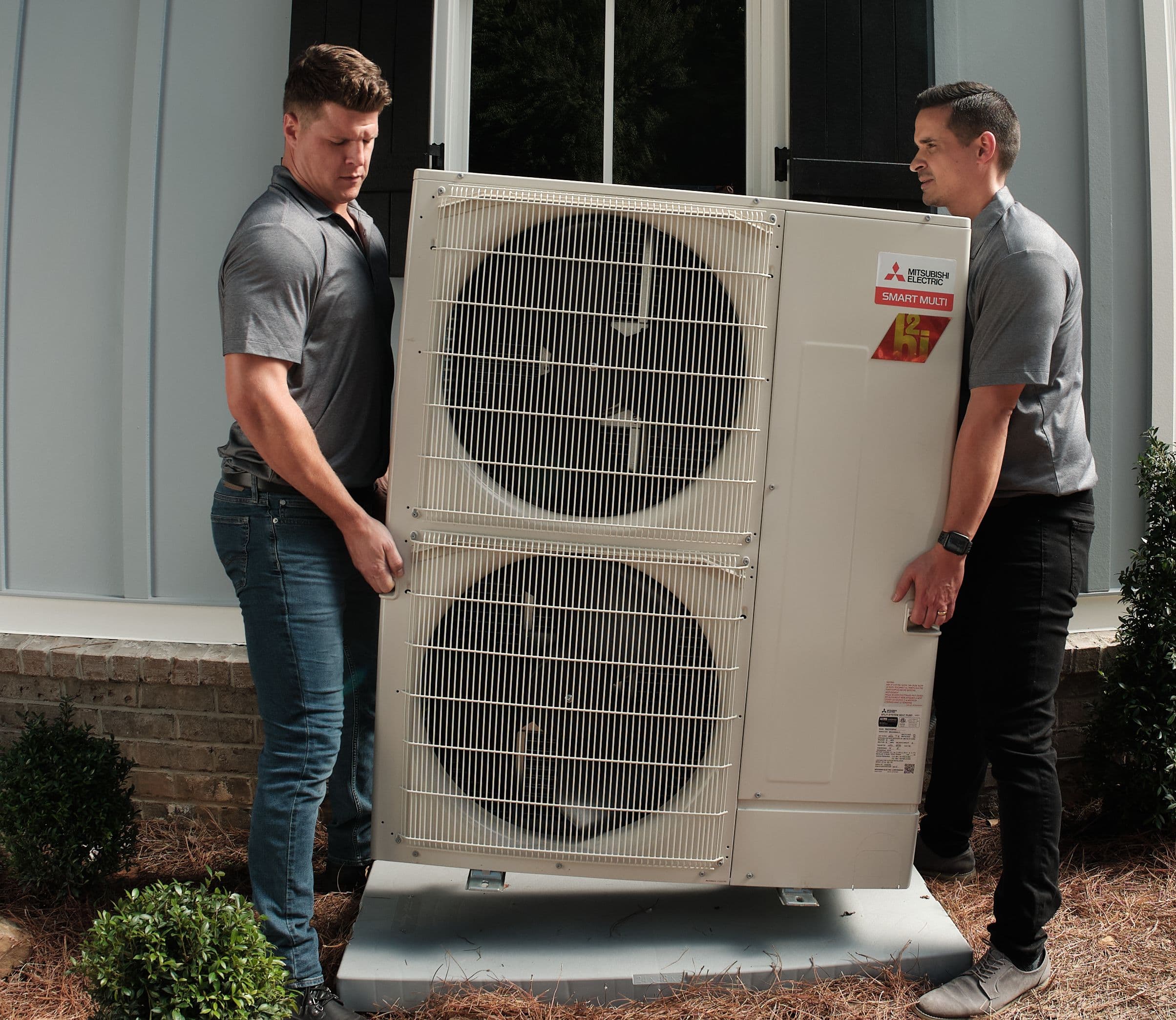 Two HVAC installers performing Mitsubishi heat pump installation.